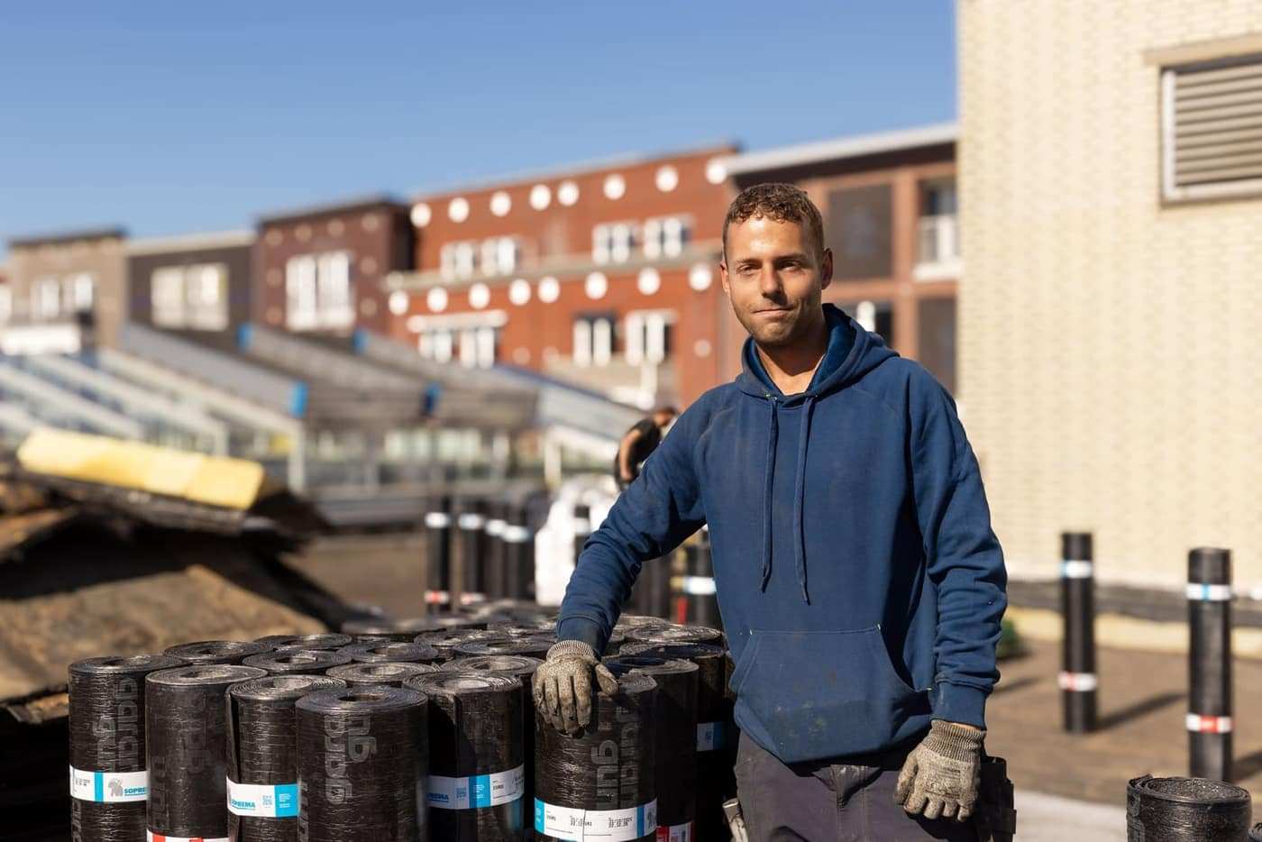 Dakdekker van Premium Dakwerken bij de voorraad bitumenrollen op een dak in uitvoering.