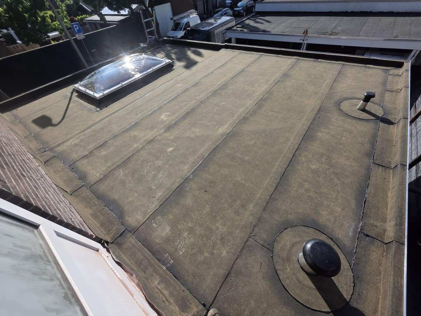 Lichtkoepel op een plat dak, met de opstand en aansluitingen rondom in beeld.