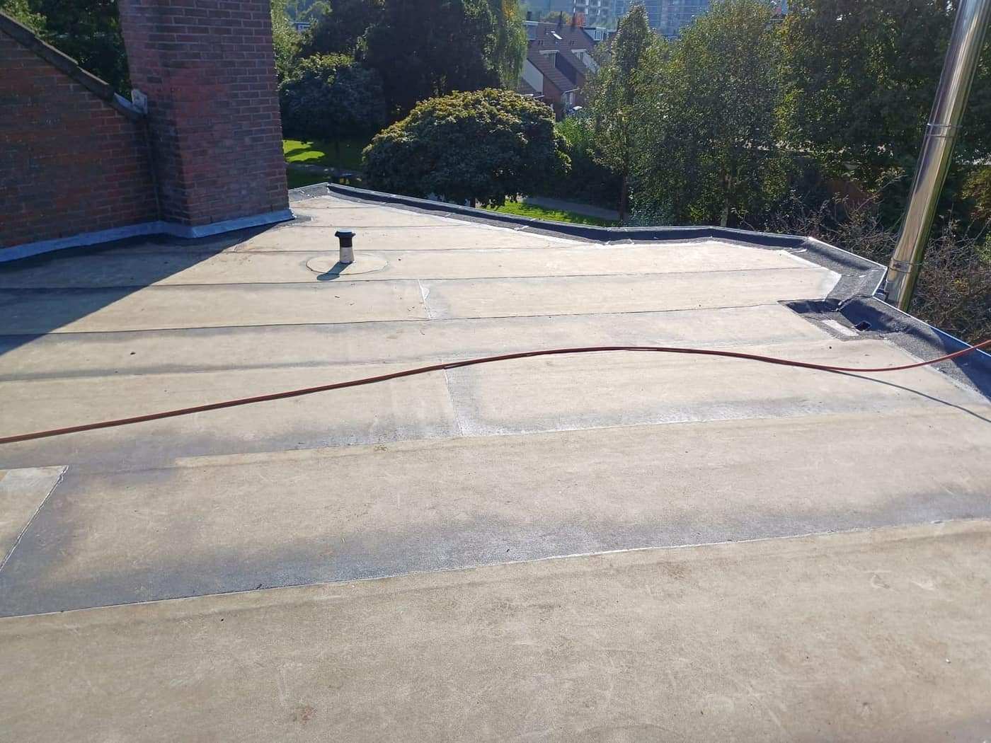 Plat dak van een woning, afgewerkt tot tegen de schoorsteen